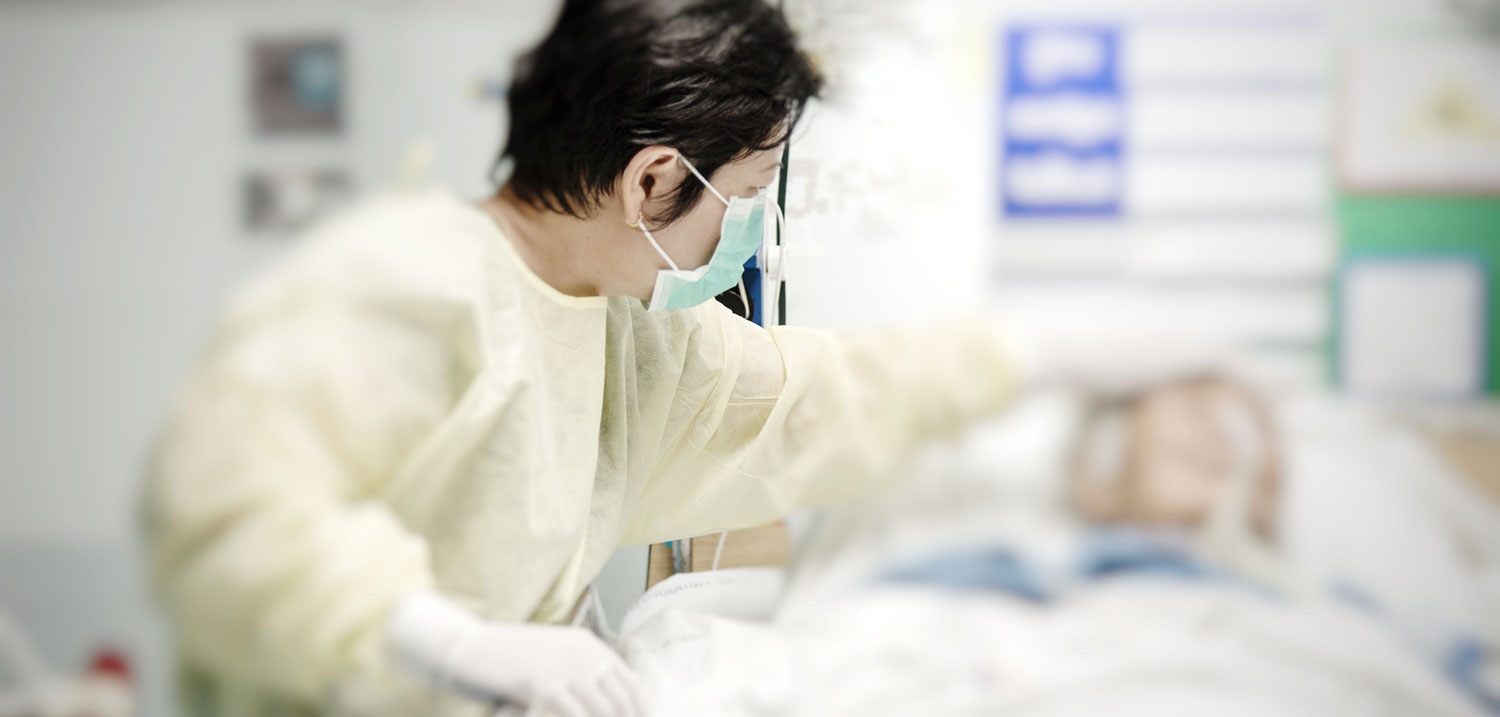 Patient in a hospital gown and mask lying on a bed, representing vulnerable ICU patients harmed by negligent intensive care.